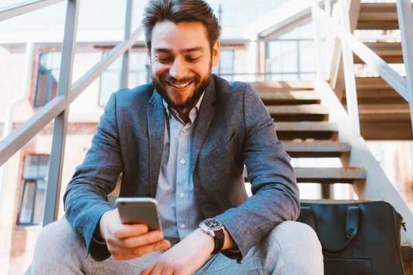 男性が笑顔でスマートフォンを触っている