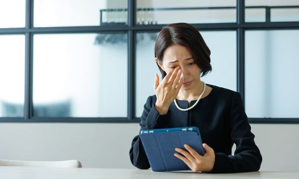 タブレットを見て悲しむ女性